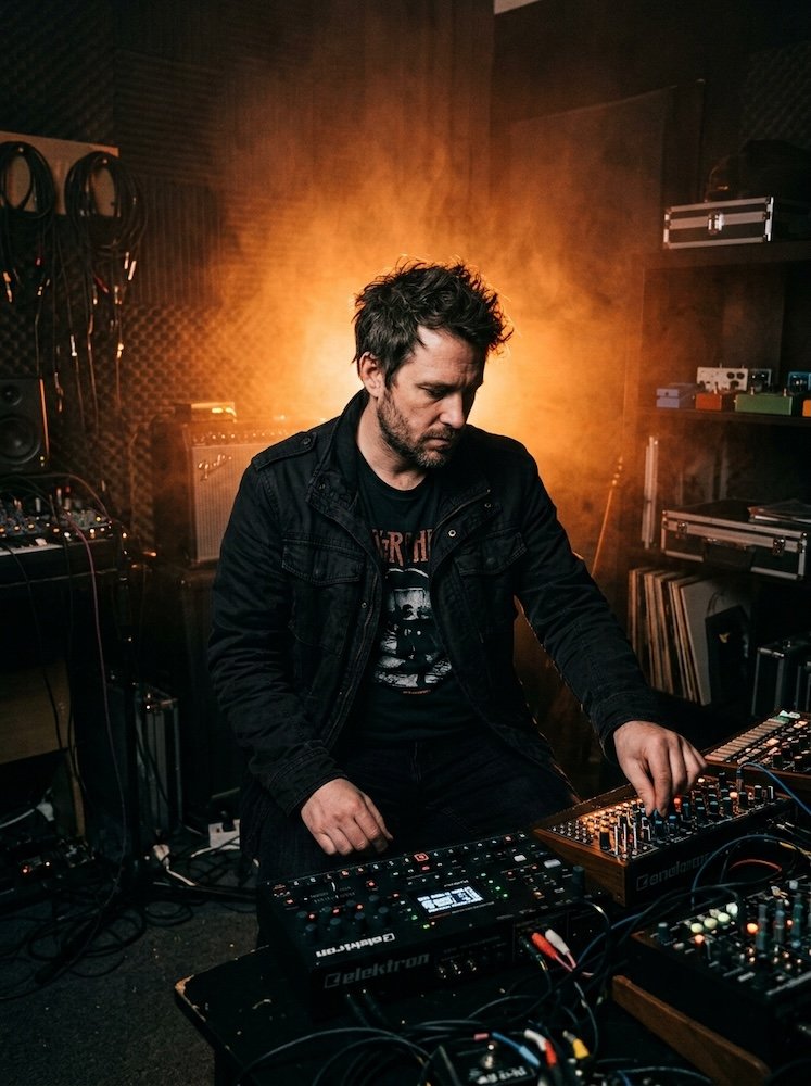 A moody musician portrait, duotone void and tangerine.
